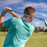 Golfeur en action sur un parcours verdoyant sous un ciel bleu