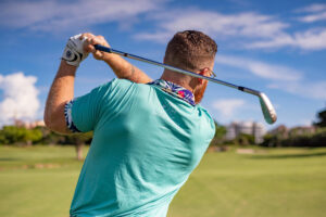 Golfeur en action sur un parcours verdoyant sous un ciel bleu