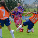 Jeunes joueuses de football en action, une tombe sur le terrain