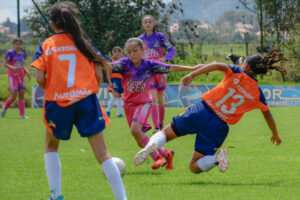 Jeunes joueuses de football en action, une tombe sur le terrain