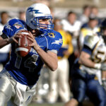 Joueur de football américain en action, portant un maillot bleu et blanc avec le numéro 14.