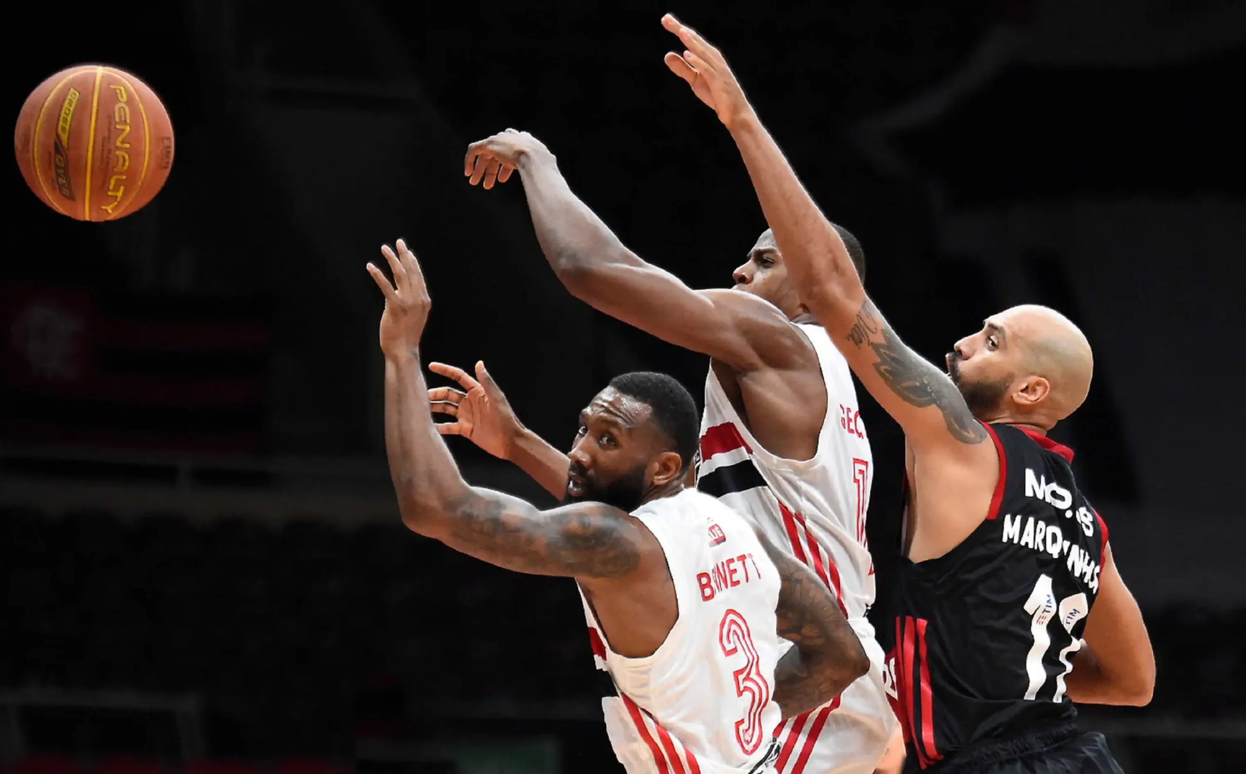 Joueurs de basketball disputant un ballon lors d'un match avec un tir contesté près du panier.