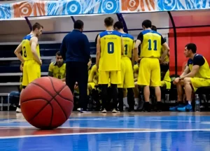 Équipe de basketball réunie autour de son entraîneur pendant un temps mort avant la reprise du match.