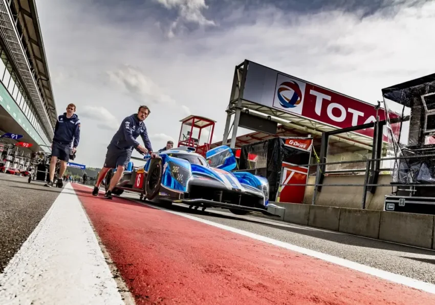 Voitures de course lancées à grande vitesse sur un circuit automobile, vues en pleine action.