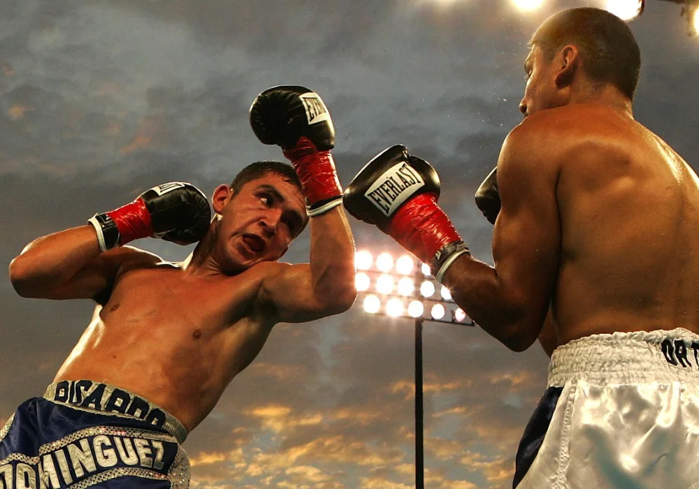 Les rivalités sportives les plus intenses de l’histoire de la boxe 2 Deux boxeurs s’affrontent dans un ring, l’un lançant un uppercut en pleine action.